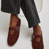Brown perforated loafers worn with black jeans on a white background