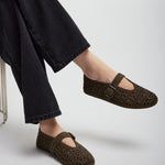 Brown perforated shoes worn with black pants on a light gray background