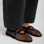 Black mesh shoes worn with black jeans on a light gray background
