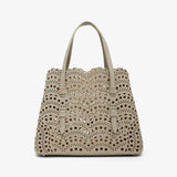 Beige handbag with decorative studs on a white background
