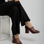 Person wearing a black outfit with brown shoes on a white background