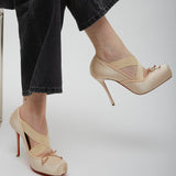 Beige high-heeled shoes worn with black pants on a light gray background