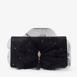 Black clutch with a large bow and star-like embellishments on a white background