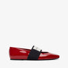Red patent leather flat shoe with a black strap on a white background