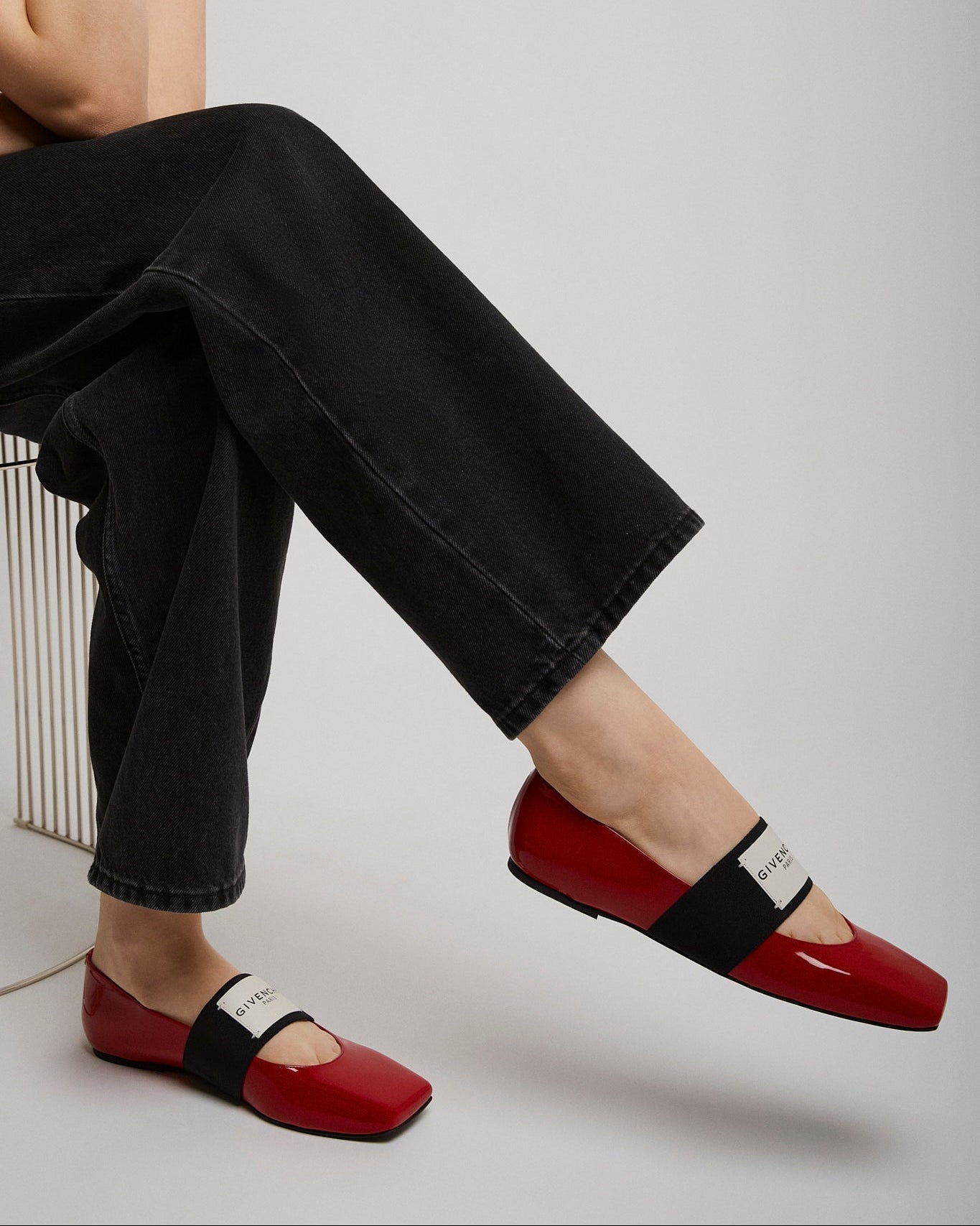 Person wearing red flats with black straps on a light gray background