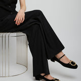 Person wearing a black outfit with wide-leg pants and black shoes on a white background