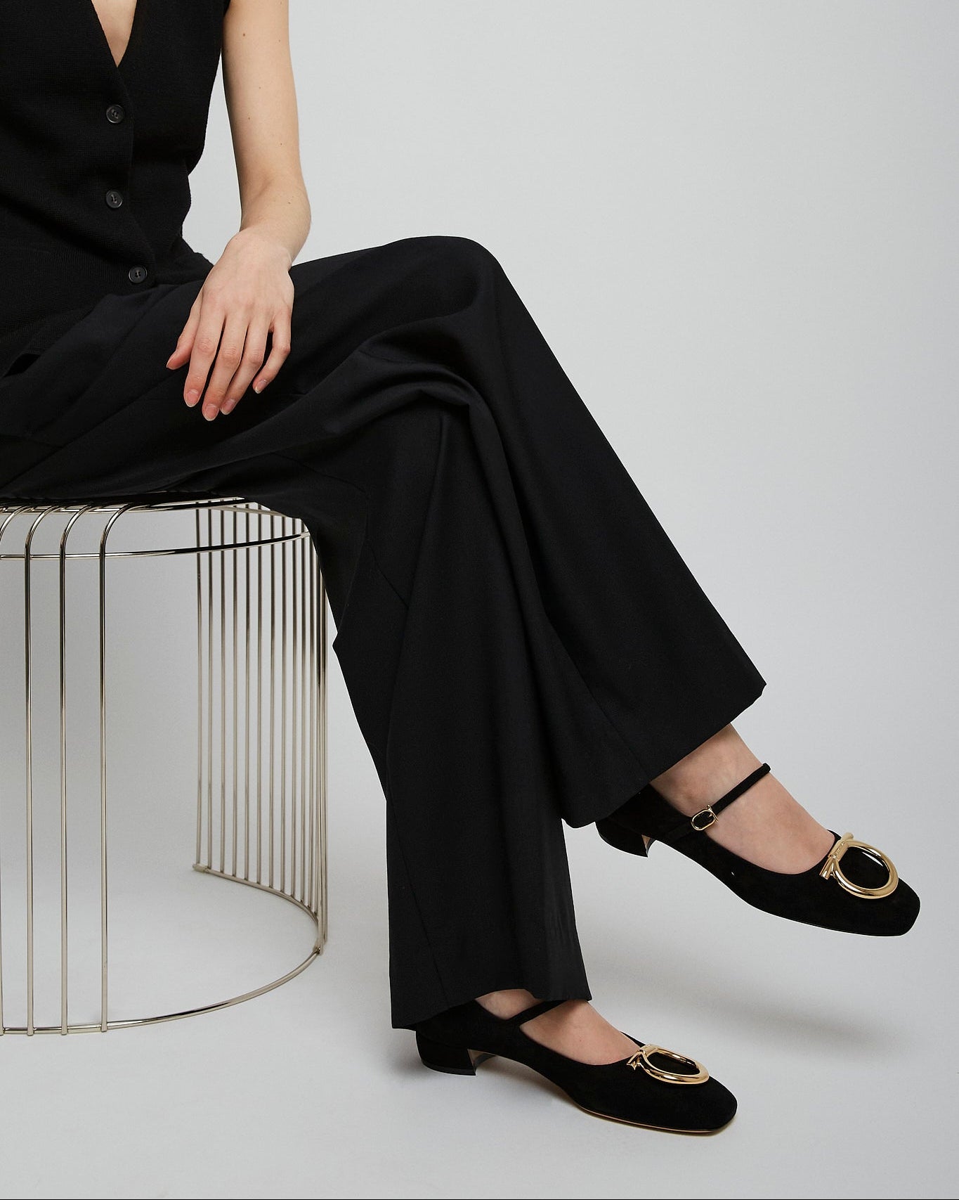 Person wearing a black outfit with wide-leg pants and black shoes on a white background
