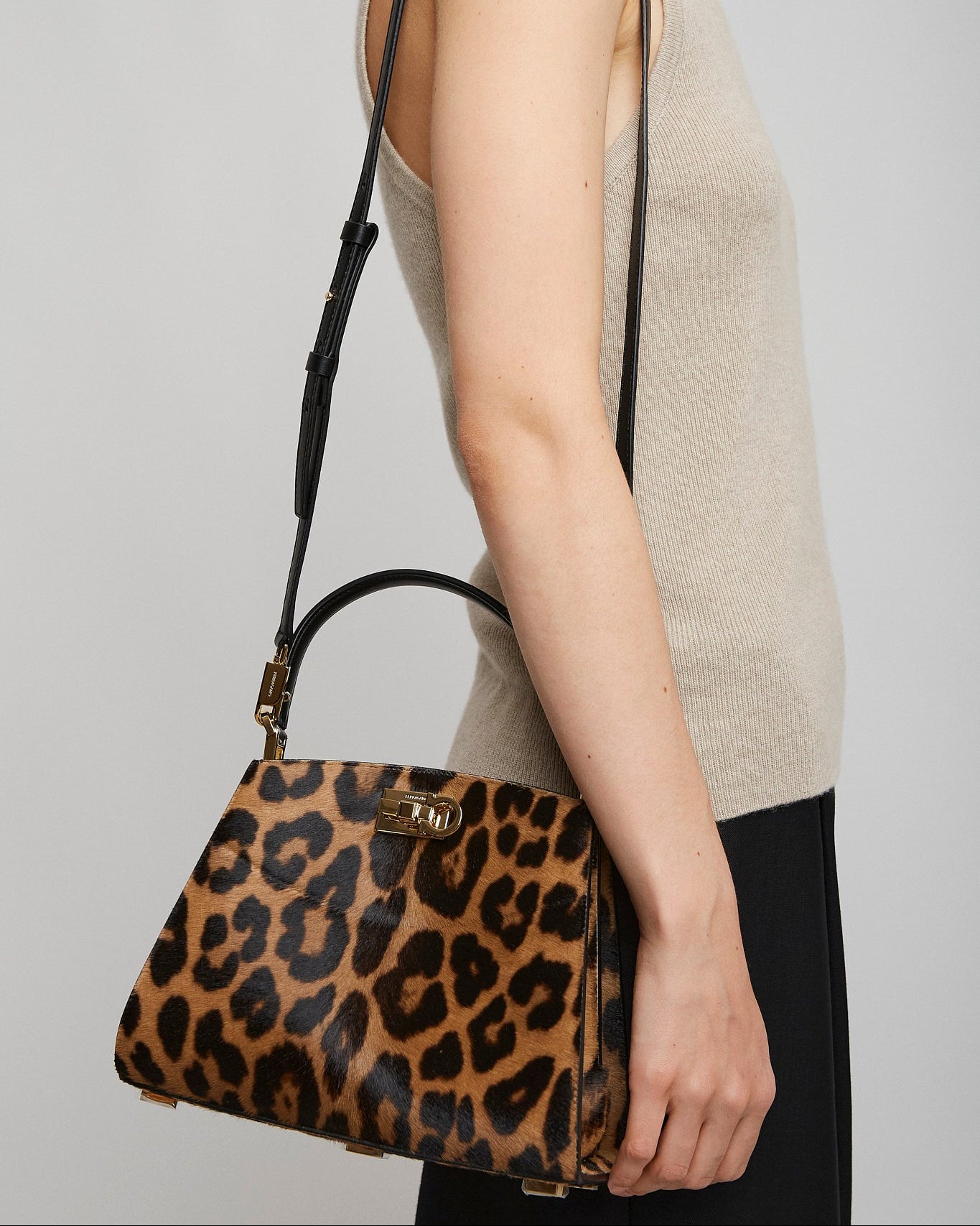 Person holding a leopard print handbag against a plain background