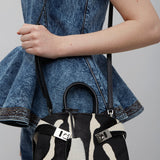 Person holding a black and white patterned handbag with a denim jacket.
