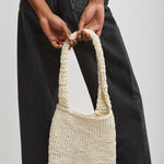 Person holding a woven handbag against a plain background