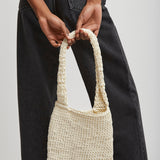 Person holding a woven handbag against a plain background