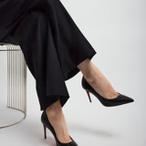 Person wearing black high heels with red soles on a white background
