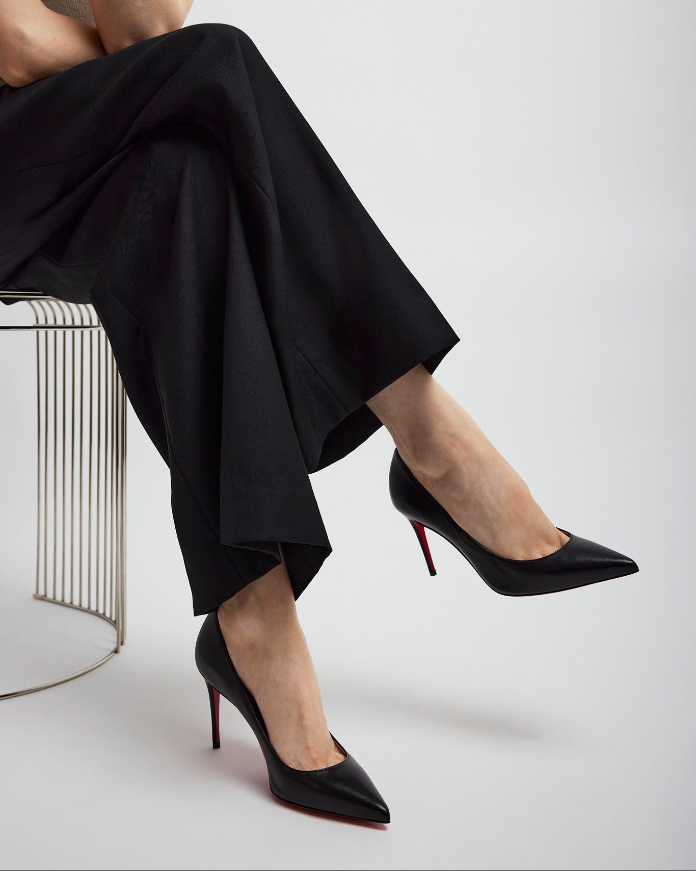 Person wearing black high heels with red soles on a white background