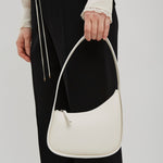 Person holding a white handbag against a plain background